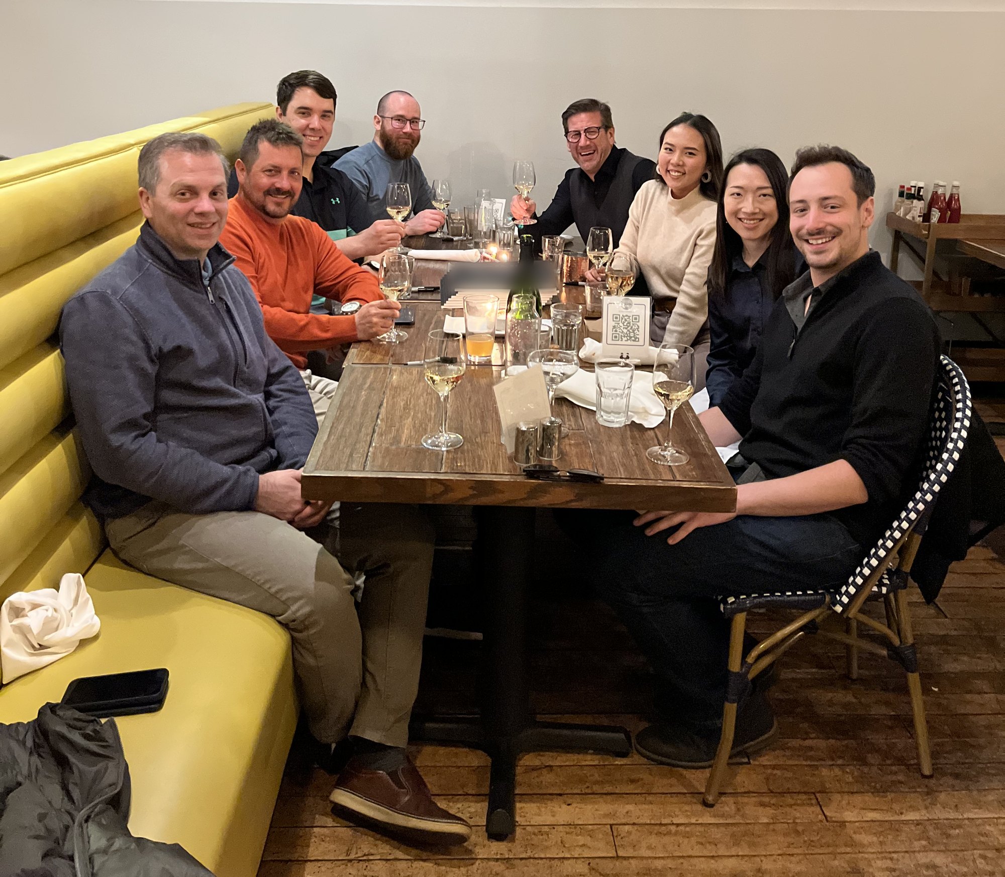 Nine peers sharing dinner and a laugh around one table
