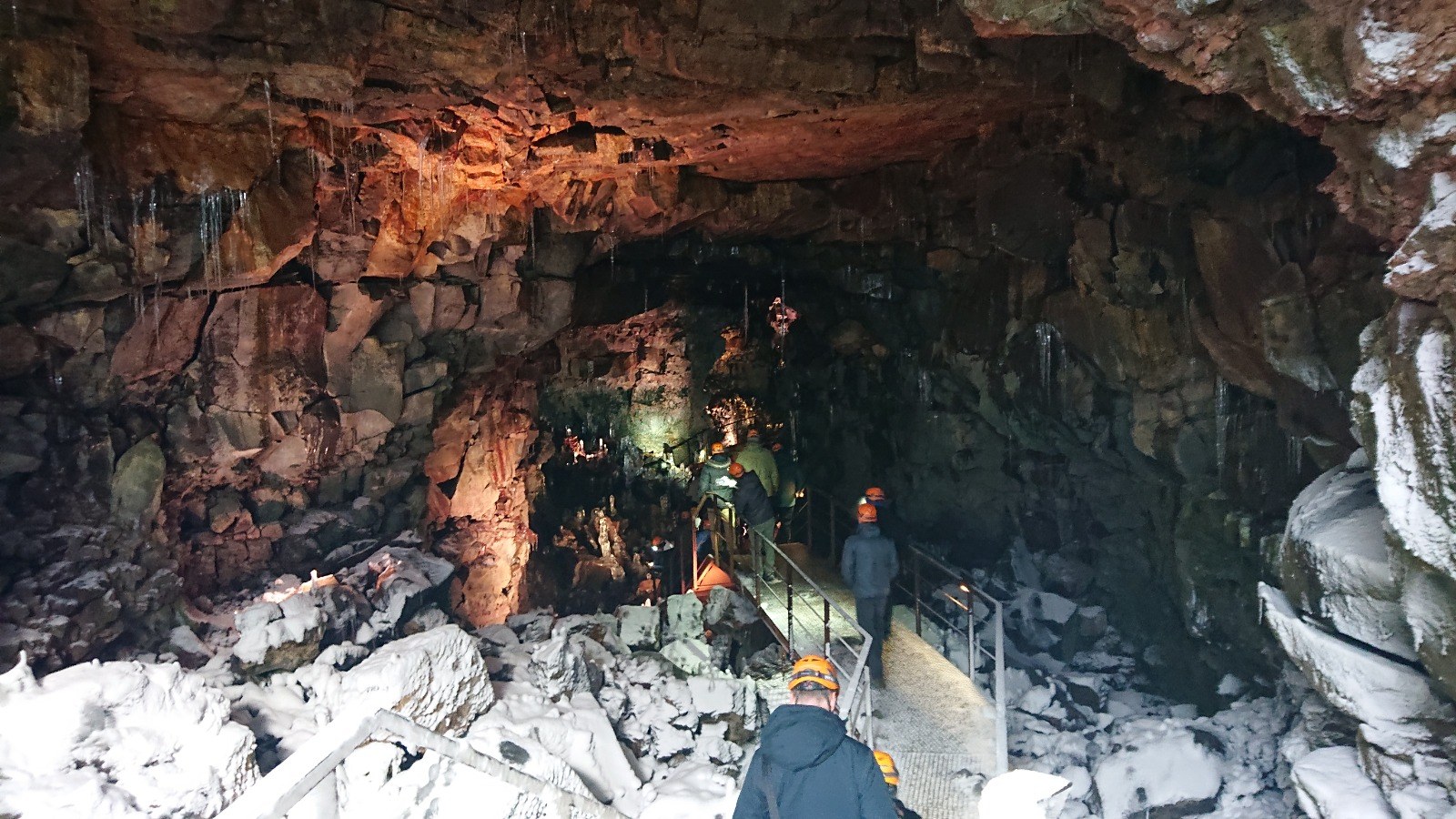 Retreat participants in helmets walking down into a lava cave